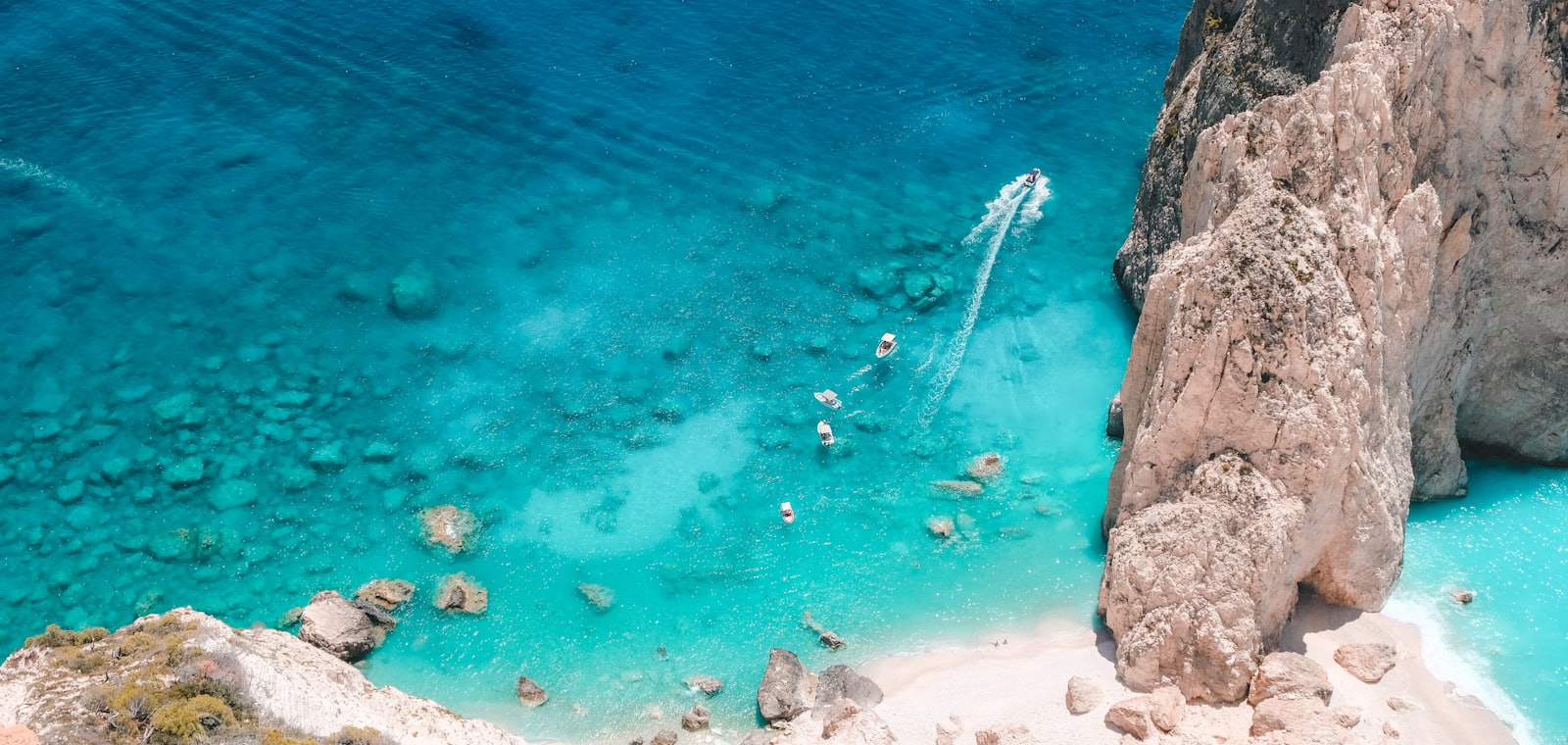 Turquoise baai met witte kliffen en bootjes aan de Griekse kust