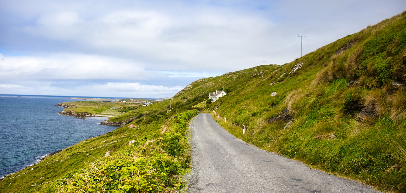 Smalle kustweg met cottage langs de groene Ierse Wild Atlantic Way